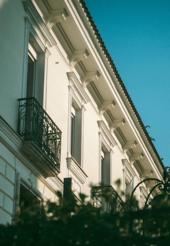 Una vista ravvicinata della facciata del Palazzo storico, caratterizzata da eleganti balconi e dettagli architettonici decorati contro un cielo azzurro e limpido.